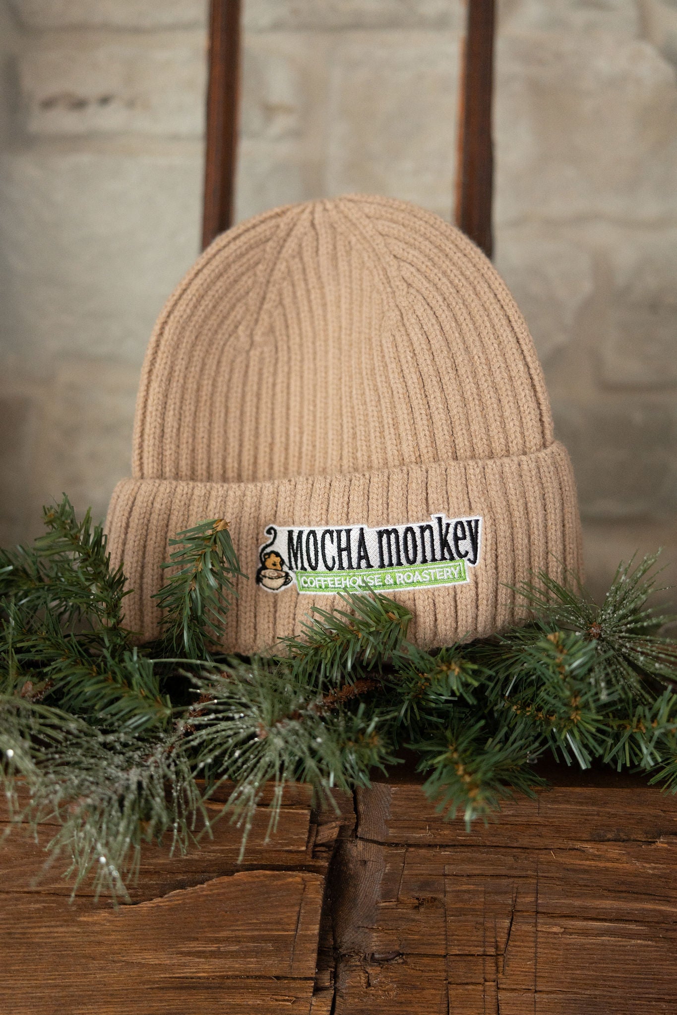 A beige wool winter beanie on pine needles
