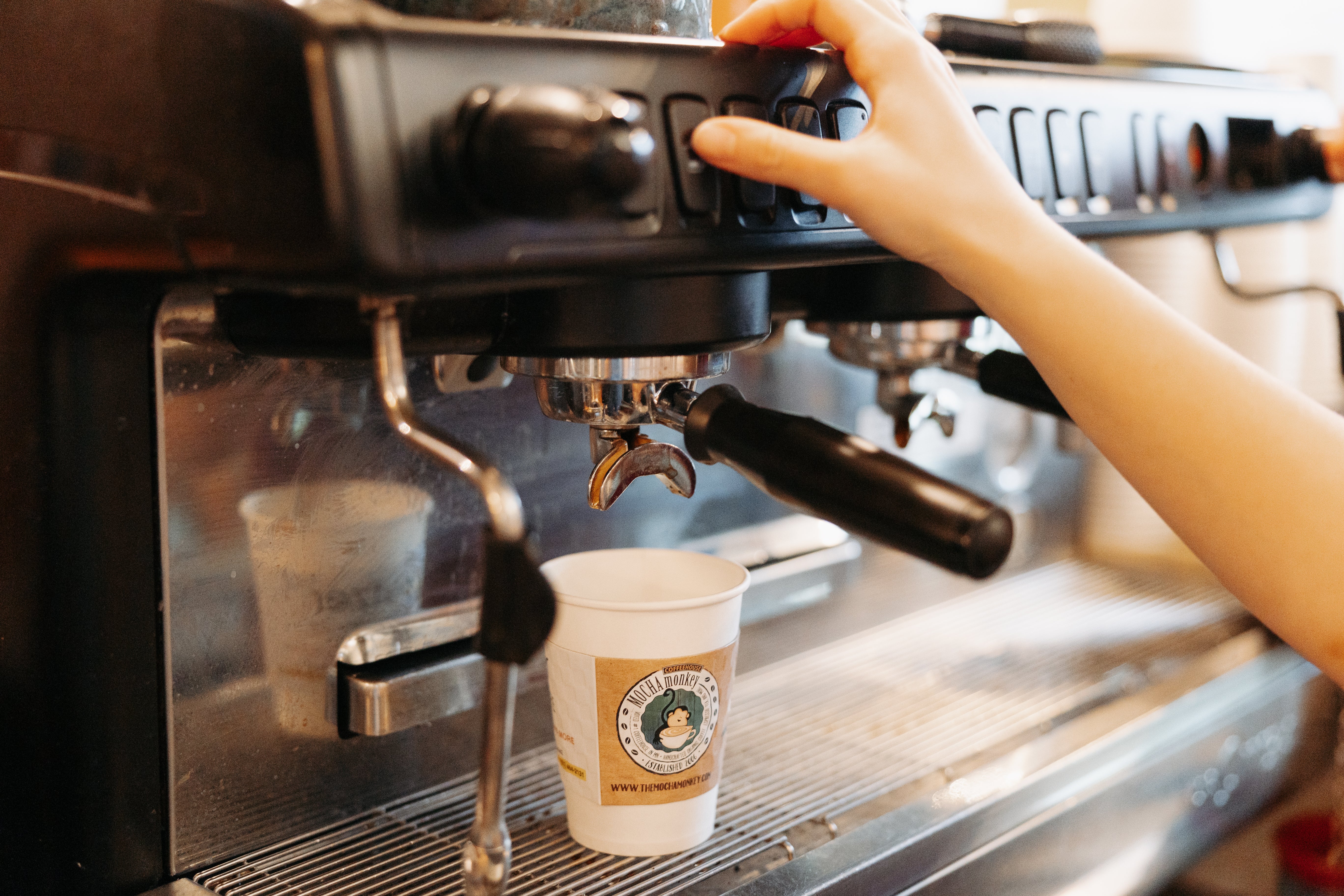 Close up of an thumb pressing a button on an espresso machine