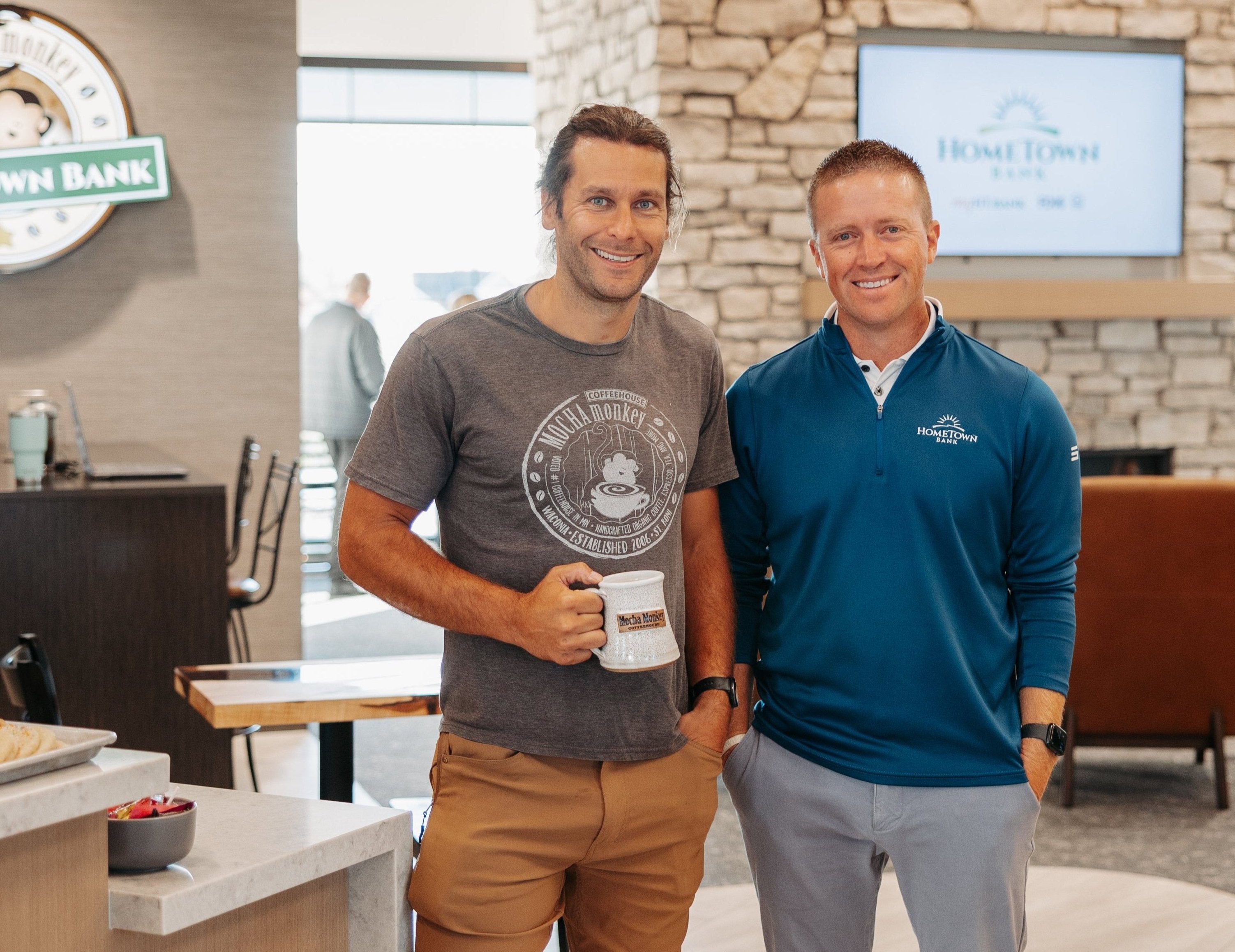 Jon holding his handmade Mocha Monkey Coffeehouse mug in the lobby of the new Mocha Monkey + Hometown Bank in Carver.