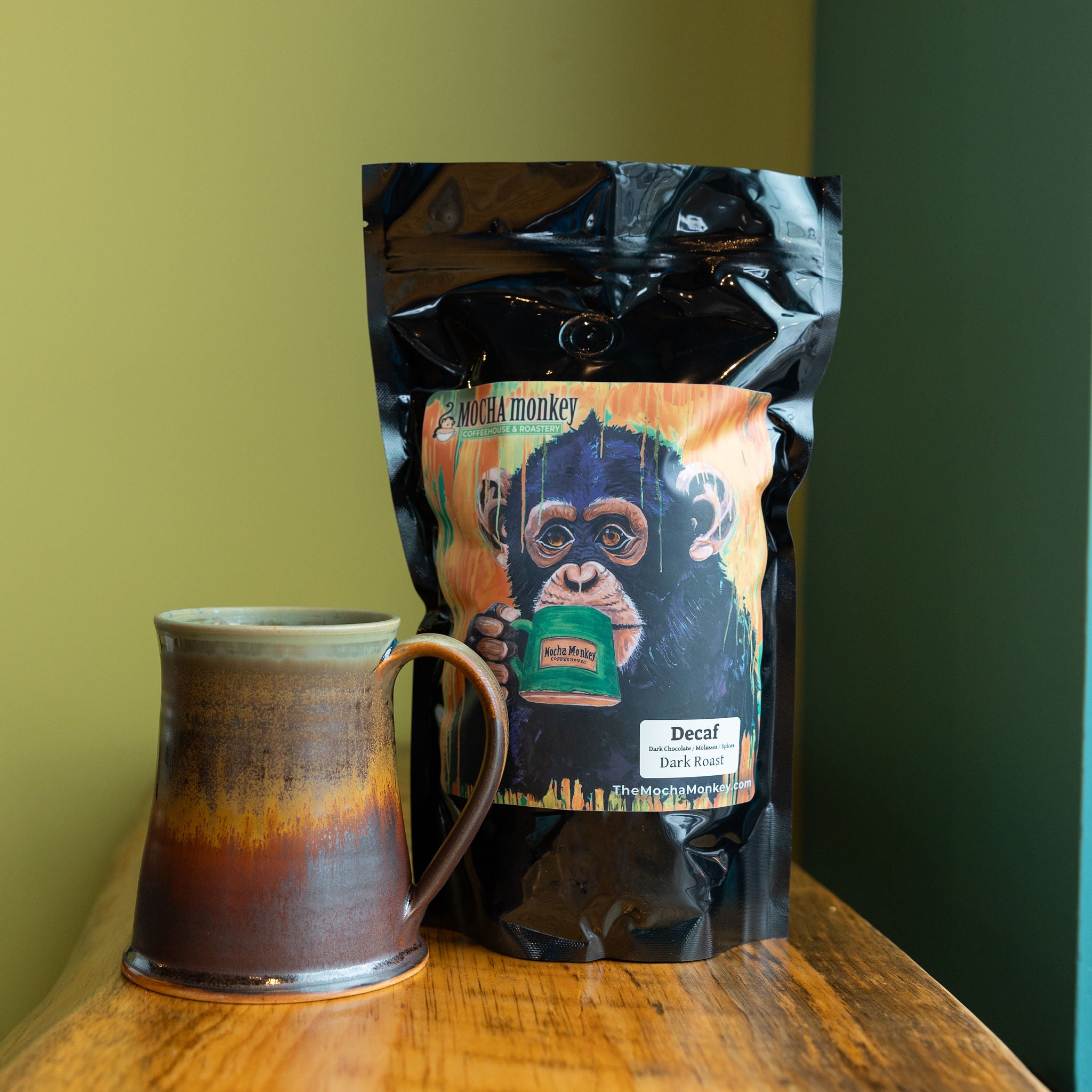 A bag of Mocha Monkey Decaf on a shelf with a coffee mug