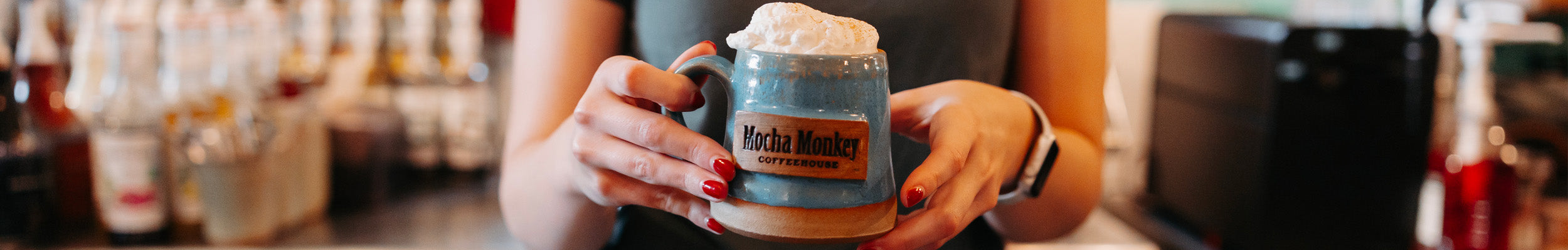 Woman holding blue Mocha Monkey Coffeehouse branded mug