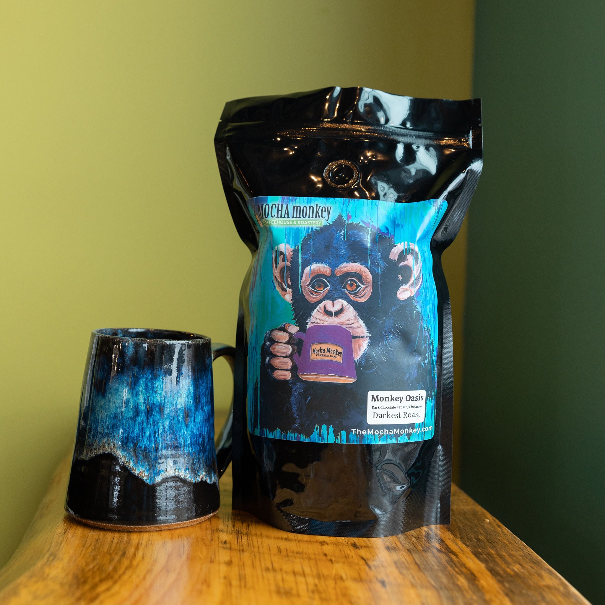 A 12oz bag of Mocha Monkey, Monkey Oasis Coffee on a shelf with a mug