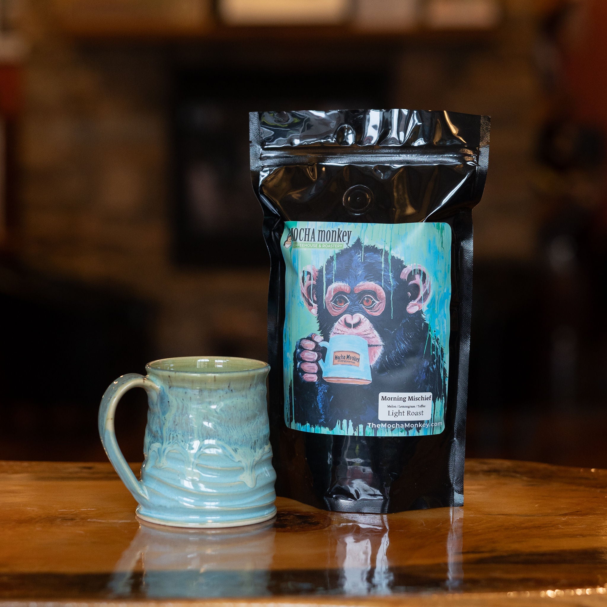 A 12oz bag of Mocha Monkey, Morning Mischief Coffee on a shelf with a mug