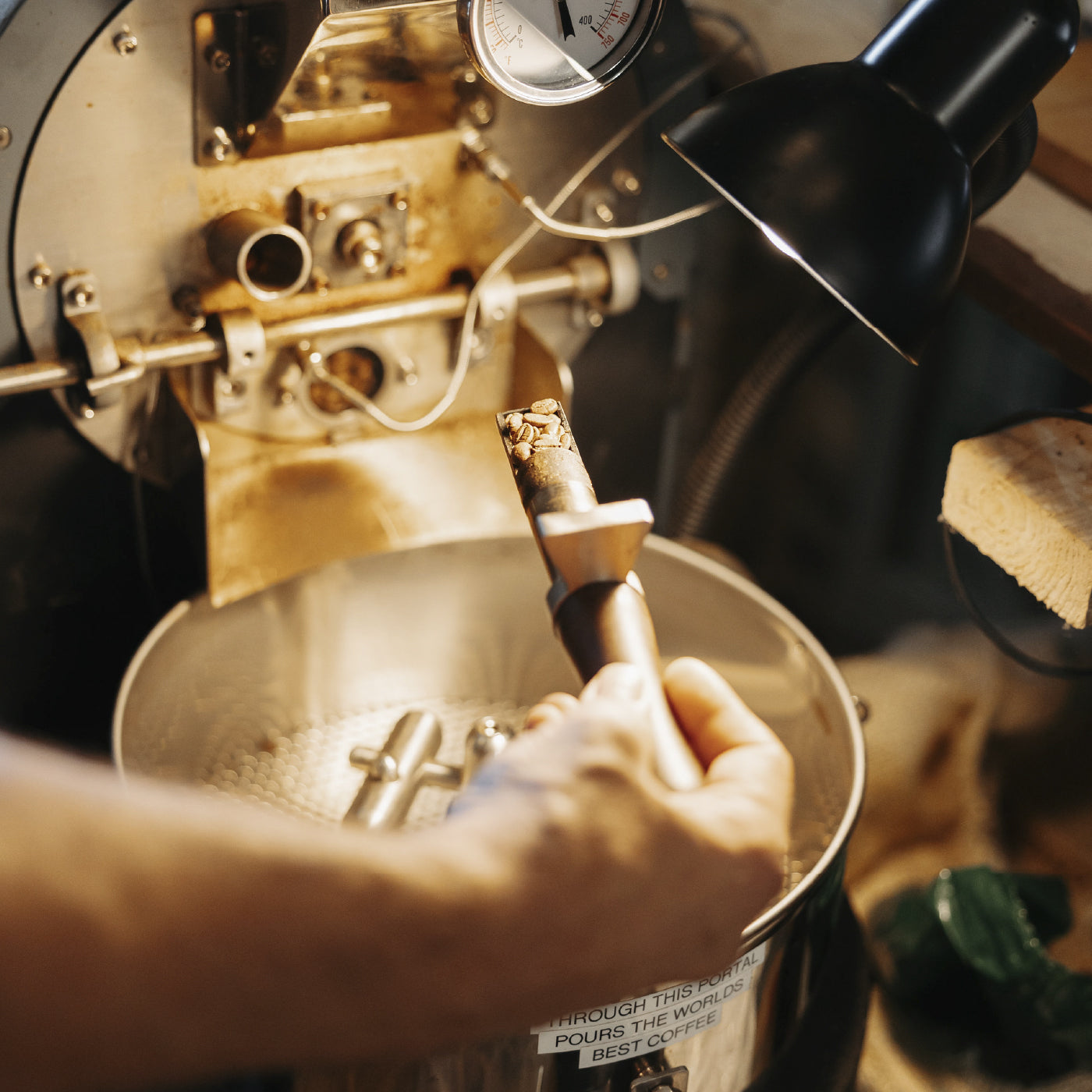 Hand holding the sample spoon of a coffee roaster