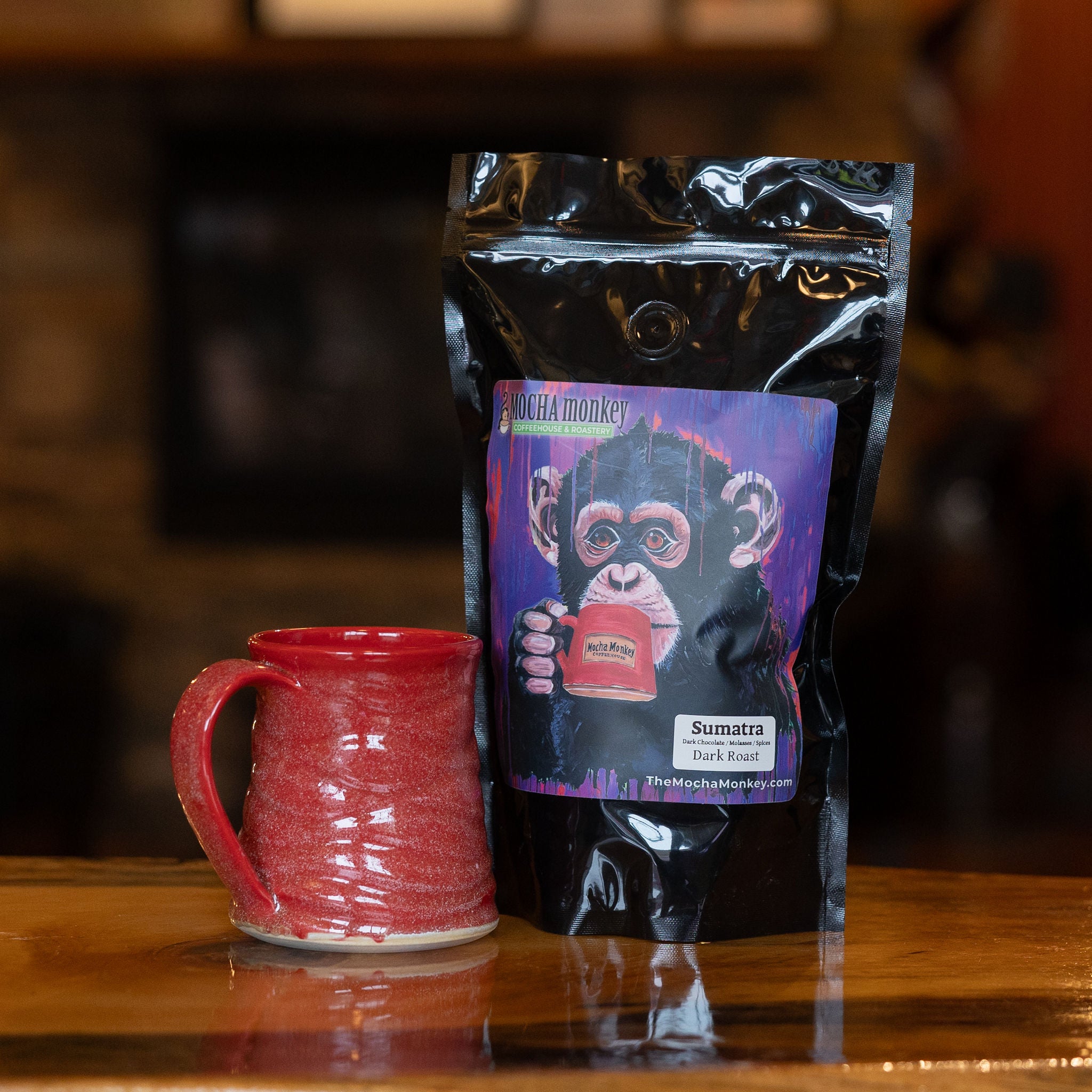 A 12oz bag of Mocha Monkey, Sumatra Coffee on a table with a mug