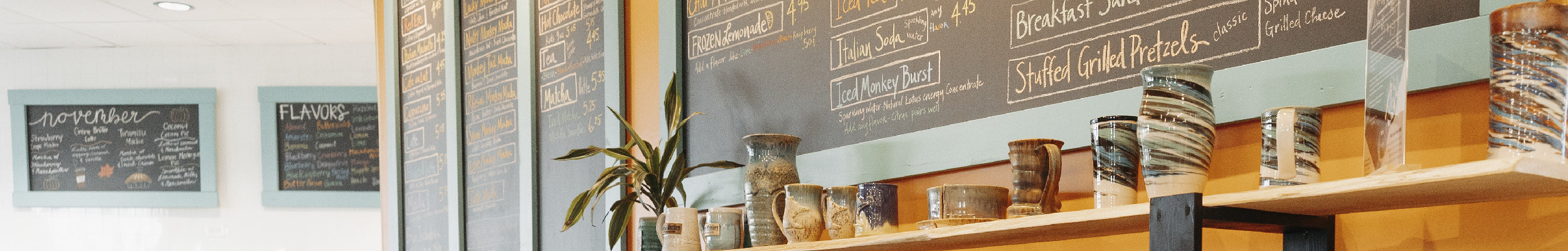 Close up of the edge of the Mocha Monkey Coffeehouse chalkboard menu and a top shelf display of handmade pottery